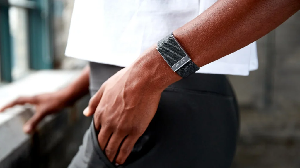 The sleek and minimalist Whoop fitness tracker displayed on a wrist, surrounded by health data visuals like heart rate and sleep charts.