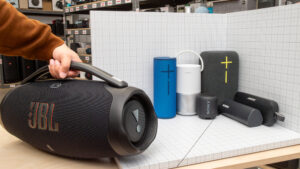 A lineup of top-rated portable wireless speakers placed outdoors and indoors, highlighting different sizes, designs, and audio performance tiers.